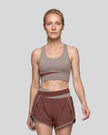 Woman wearing TrackLine Synergy Racerback Sports Bra in Gray Purple with Brick Red detail, front view