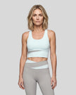 Woman wearing TrackLine Synergy Racerback Sports Bra in Light Blue with Light Gray detail, front view