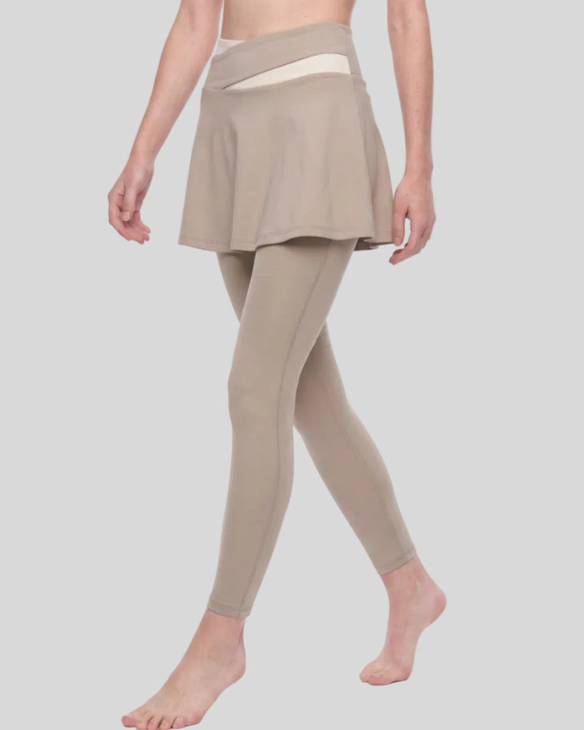 Woman wearing TrackLine Synergy Skirted Leggings in Light Coffee with Apricot crossover waistband, lower body angled front view