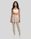 Woman wearing TrackLine Synergy Skirted Leggings in Light Coffee with Apricot crossover waistband, front view