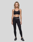 Woman wearing TrackLine Synergy Strappy Sports Bra in Black, full-body front view