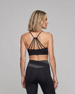 Woman wearing TrackLine Synergy Strappy Sports Bra in Black, mid-body back view showing multi-strap detail