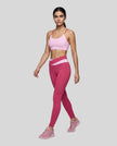 Woman wearing TrackLine Synergy Strappy Sports Bra in Pink with Rose Red, angled full-body front view