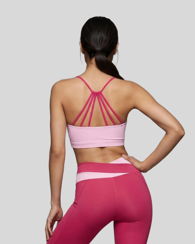 Woman wearing TrackLine Synergy Strappy Sports Bra in Pink with Rose Red, mid-body back view showing multi-strap detail