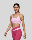 Woman wearing TrackLine Synergy Strappy Sports Bra in Pink with Rose Red, angled mid-body front view