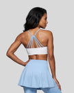 Woman wearing TrackLine Synergy Strappy Sports Bra in White with Sky Blue, mid-body back view showing multi-strap detail