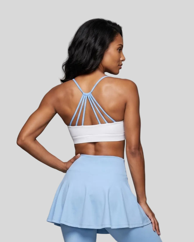 Woman wearing TrackLine Synergy Strappy Sports Bra in White with Sky Blue, mid-body back view showing multi-strap detail