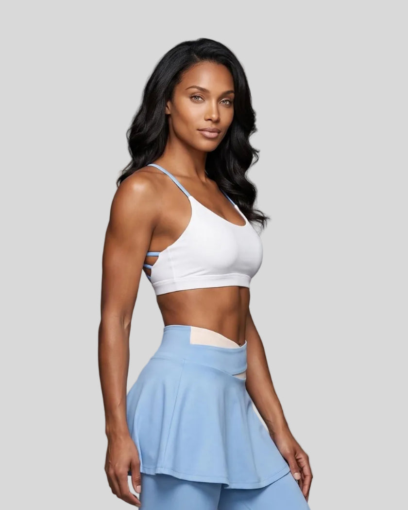 Woman wearing TrackLine Synergy Strappy Sports Bra in White with Sky Blue angled mid-body front view