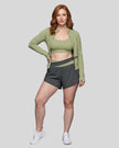 Woman modeling a Bean Grean with Dark Gray TrackLine Synergy Tank Top with matching shorts and jacket, paired with white sneakers.