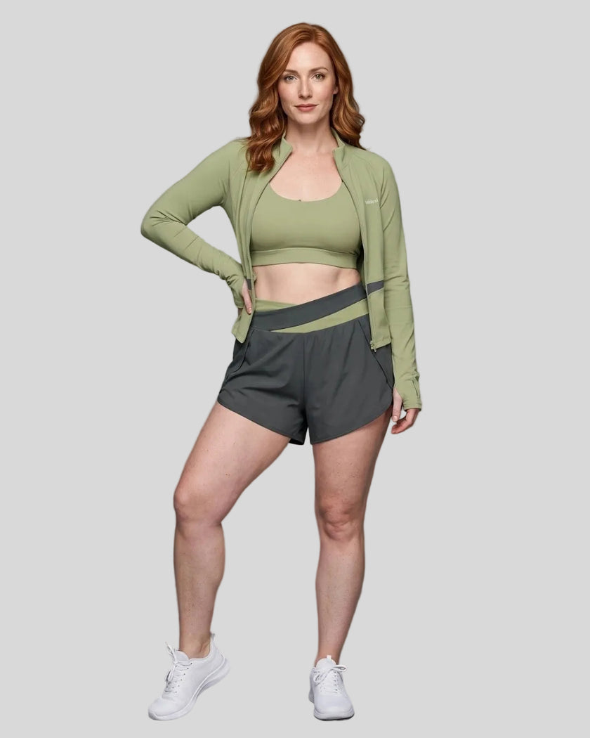 Woman modeling a Bean Grean with Dark Gray TrackLine Synergy Tank Top with matching shorts and jacket, paired with white sneakers.