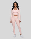 Woman modeling a Light Pink with Apricot TrackLine Synergy Tank Top with matching leggings and jacket, paired with white sneakers.