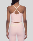 Woman wearing TrackLine Synergy Tank Top in Light Pink with Apricot crossover straps, back view