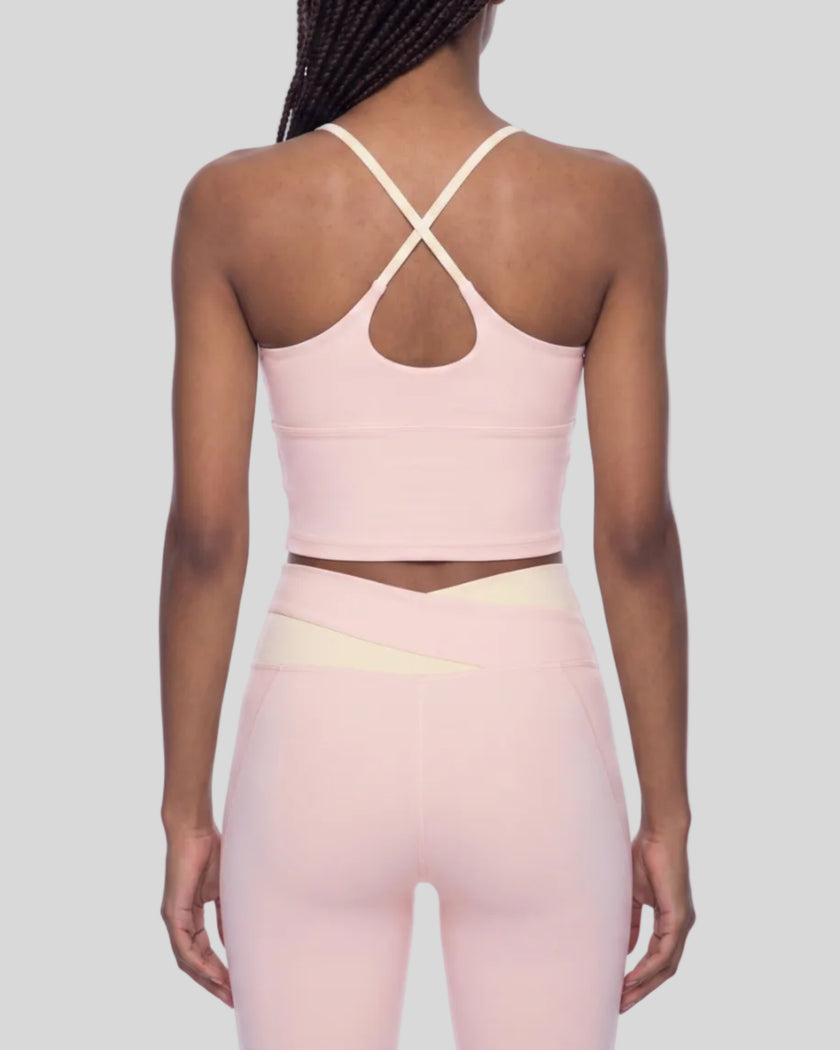 Woman wearing TrackLine Synergy Tank Top in Light Pink with Apricot crossover straps, back view