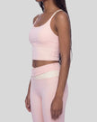 Woman wearing TrackLine Synergy Tank Top in Light Pink with Apricot straps, angled side view