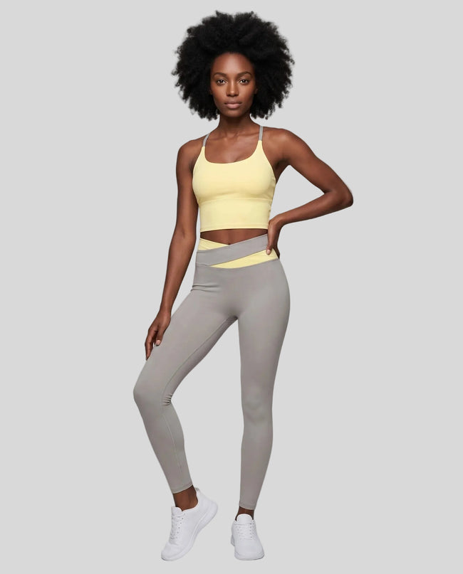 Woman modeling a Light Yellow with Light Gray TrackLine Synergy Tank Top and matching leggings, paired with white sneakers.