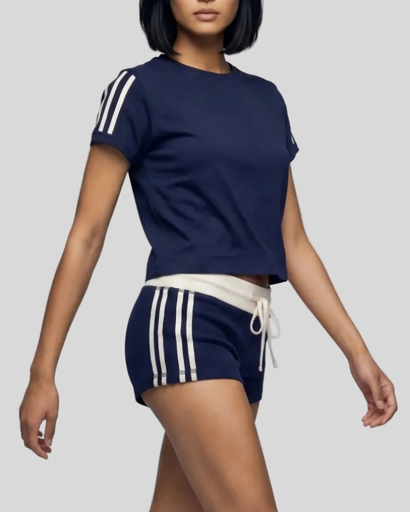 Mid body front angle view of the Athlesi TrackLine Track Shorts in blue styled with the TrackLine Varsity Tee