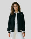 Model wearing the TrackLine Varsity Jacket in Black partially open front view