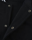 Snap-button front closure detail on the TrackLine Varsity Jacket in Black