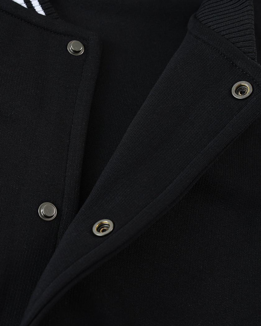 Snap-button front closure detail on the TrackLine Varsity Jacket in Black