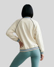 Back view of a model wearing the TrackLine Varsity Jacket in Mild Apricot