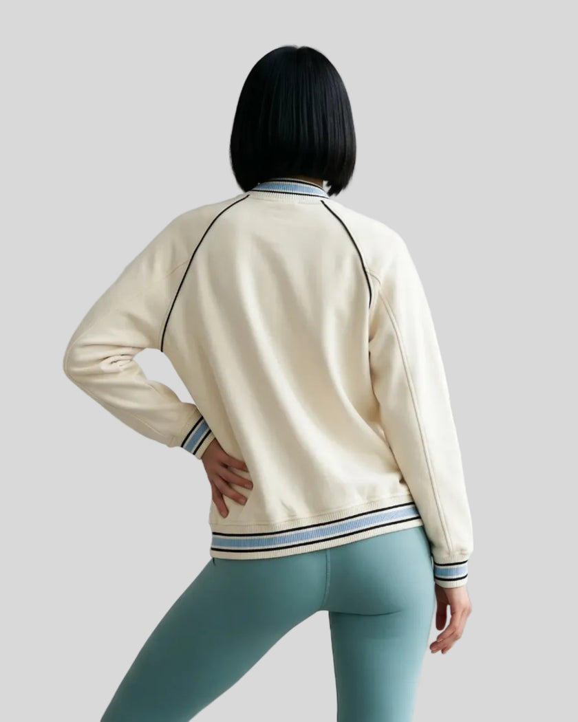 Back view of a model wearing the TrackLine Varsity Jacket in Mild Apricot