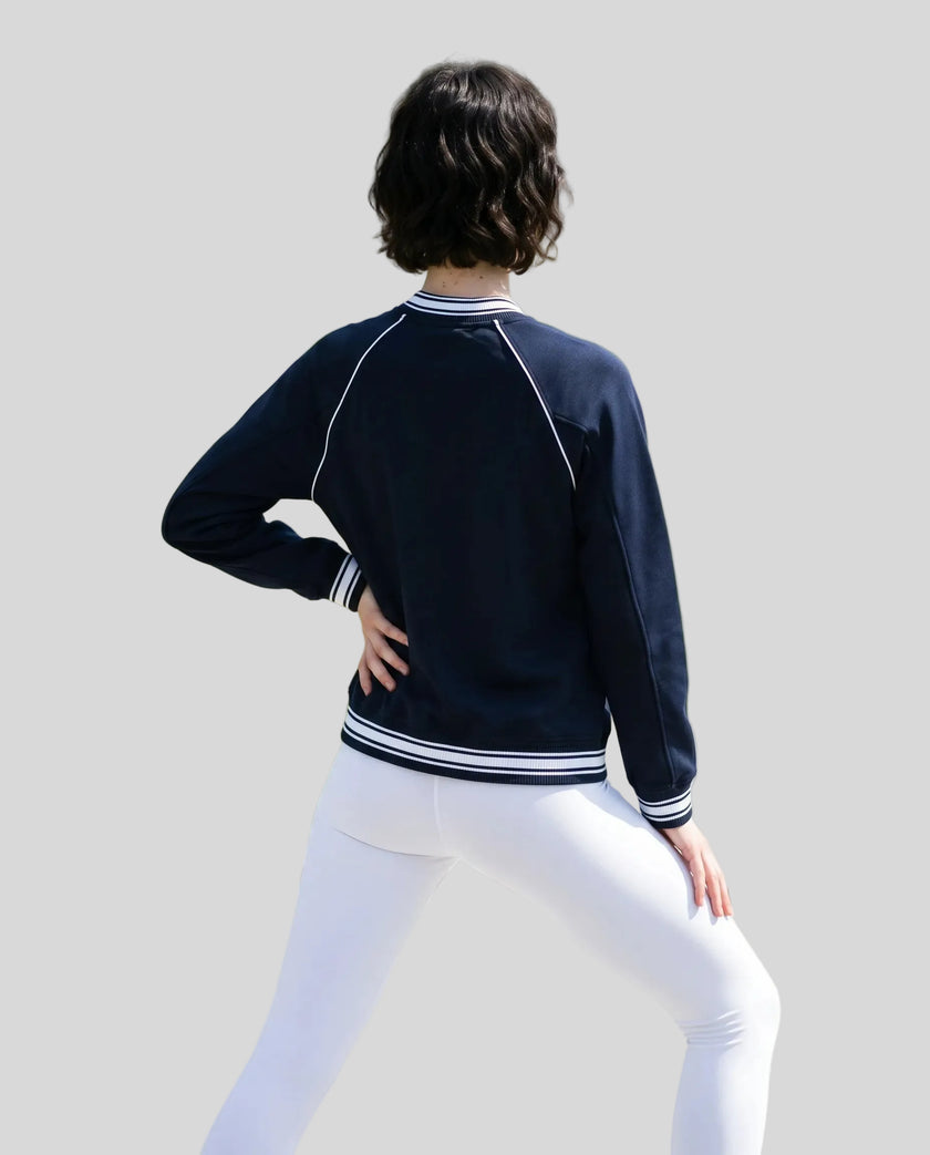 Back view of a model wearing the TrackLine Varsity Jacket in Navy Blue
