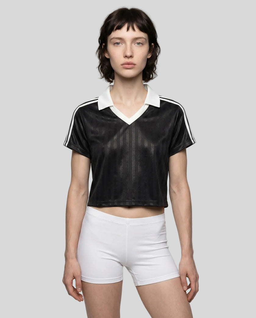 Mid body front view of a woman wearing the Athlesi TrackLine Varsity Jersey in black and white