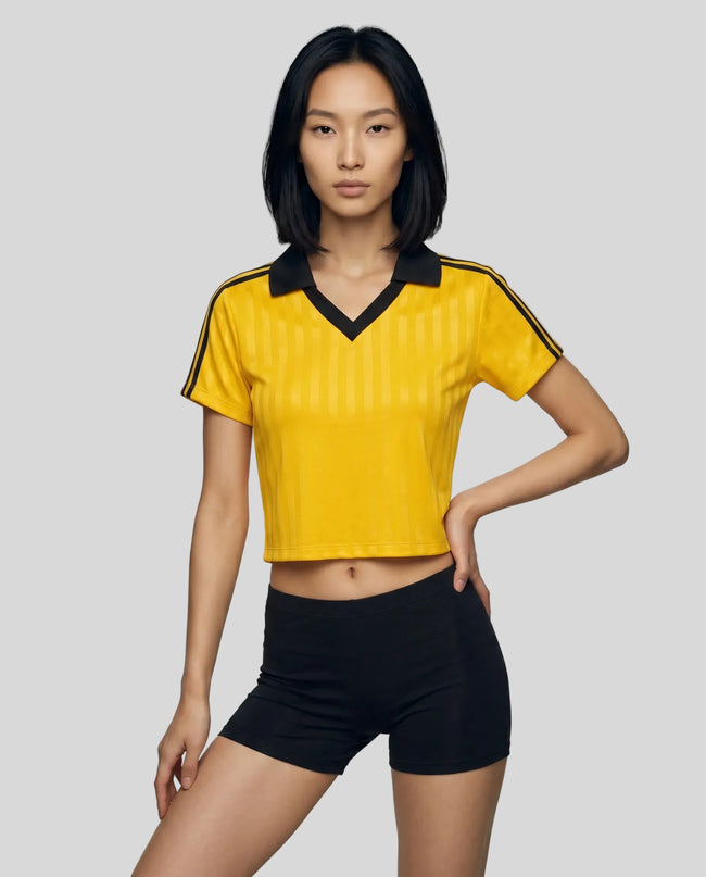 Mid body front view of a woman wearing the Athlesi TrackLine Varsity Jersey in yellow and black