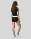 Full body back view of the Athlesi TrackLine Varsity Tee in black in a clean modern architectural environment