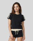 Upper body front view of a woman wearing the Athlesi TrackLine Varsity Tee in black