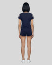Full body back view of the Athlesi TrackLine Varsity Tee in blue in a clean modern architectural environment