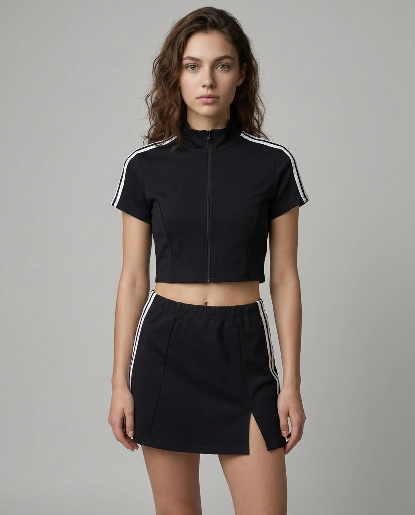Woman wearing the Athlesi TrackLine Zip Crop Tee in white styled with Athlesi TrackLine Slit Skirt, in a modern minimalist setting