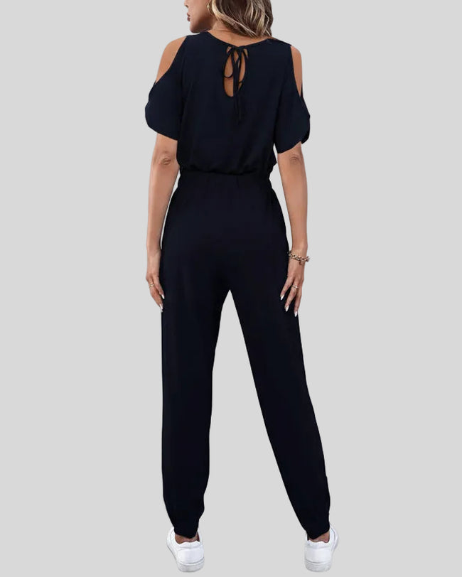 Back view of dark blue cold-shoulder jumpsuit with adjustable waist tie
