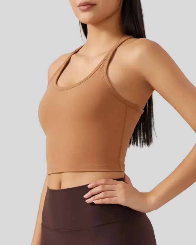 Person wearing a brown sports bra and dark leggings on a light gray background