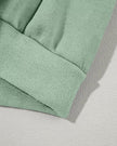 Jacket waistband close-up showing relaxed hem structure in sage